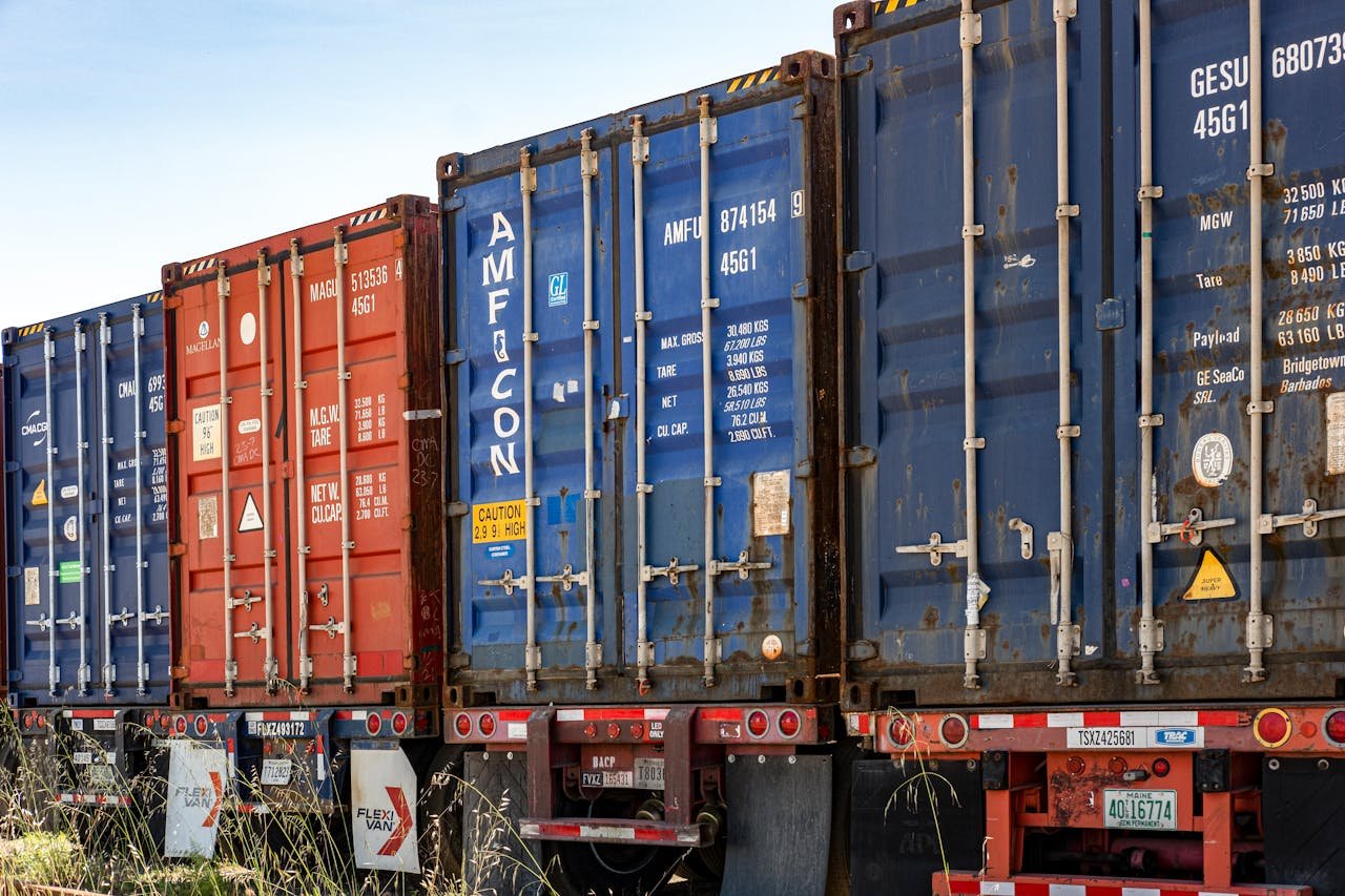 Services-02 Row of colorful cargo containers in an industrial shipping yard, ready for transportation.